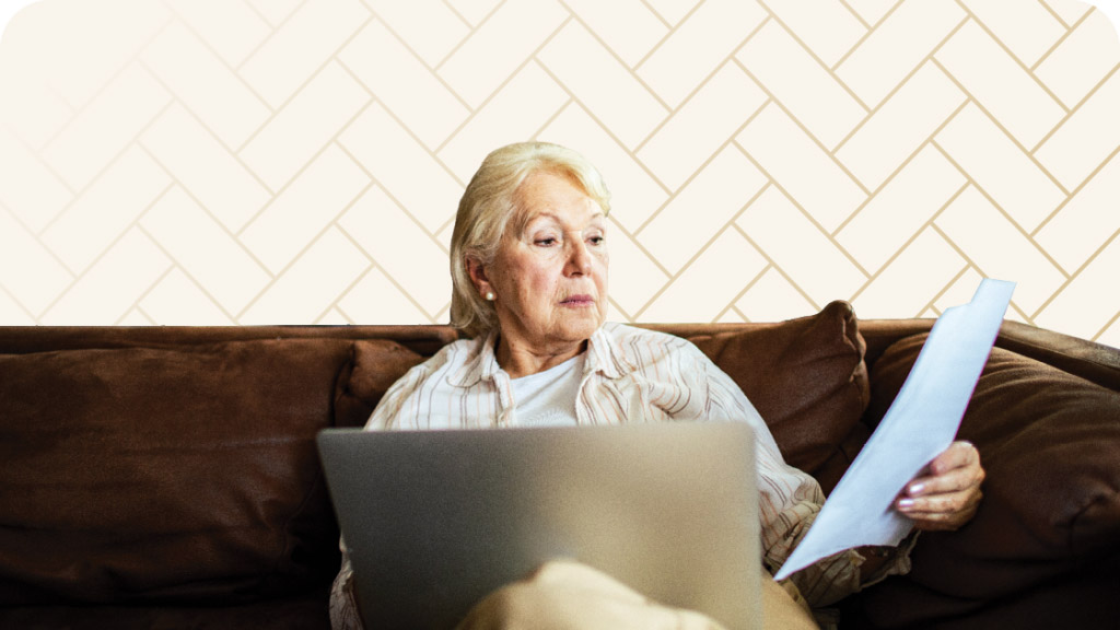 Senior woman sitting on couch with laptop comparing Kennewick senior living costs